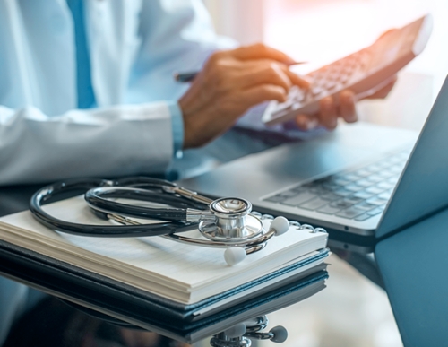 A doctor is using his phone while sitting at the desk.